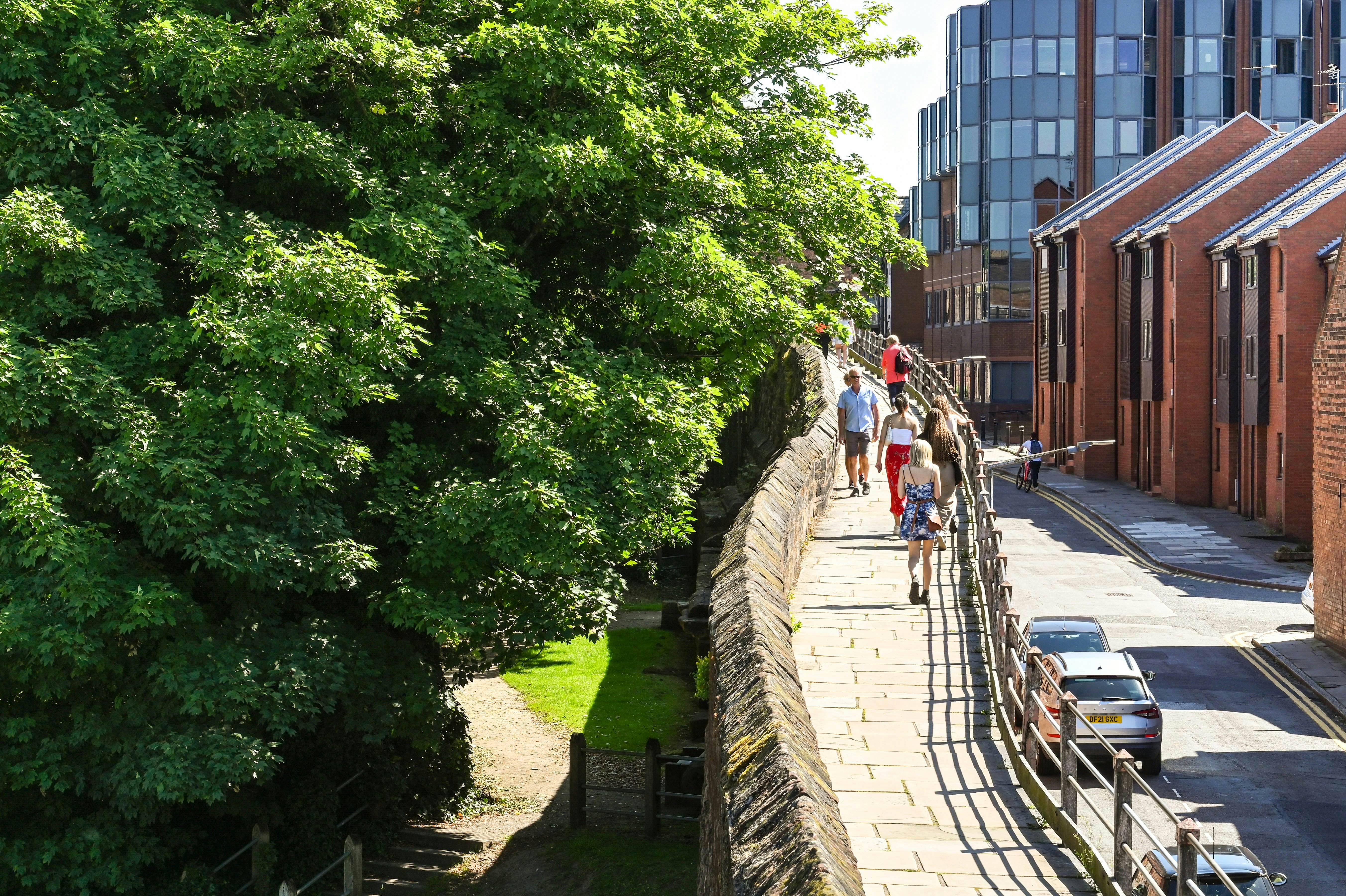 Chester, England - July 2021: Visitors walking on an elevated section of  the walk around the city's old wall.